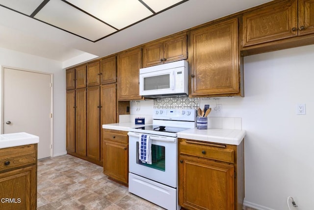 kitchen featuring brown cabinetry, white appliances, and tile countertops