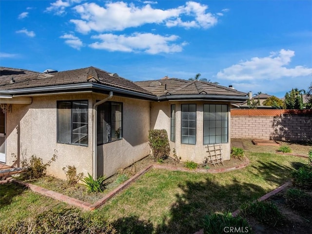 view of property exterior with a yard, fence, and stucco siding