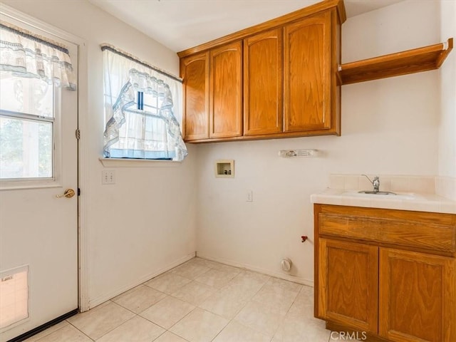 laundry area with cabinet space, baseboards, washer hookup, and a sink