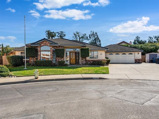 view of front of house featuring driveway, a tiled roof, an attached garage, a front yard, and stucco siding