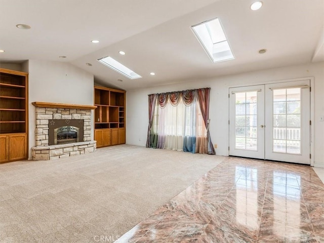 unfurnished living room with french doors, lofted ceiling, recessed lighting, light carpet, and a stone fireplace