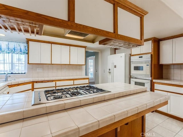 kitchen featuring tile countertops, white appliances, and white cabinetry