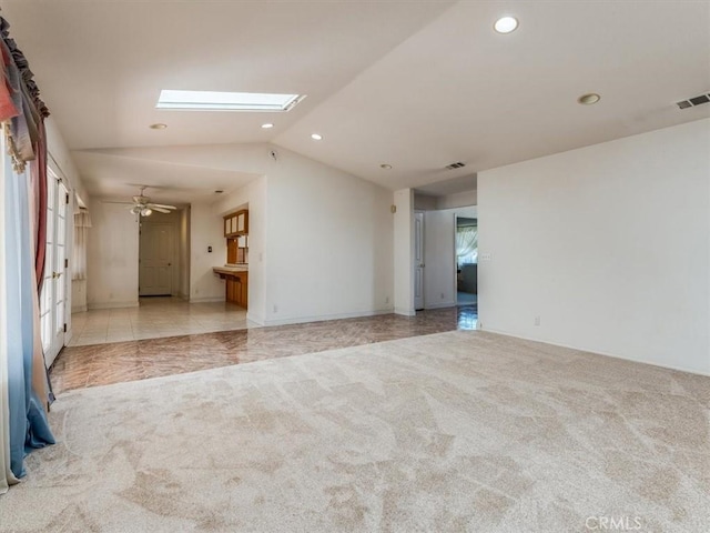 empty room with light carpet, light tile patterned floors, vaulted ceiling with skylight, visible vents, and recessed lighting