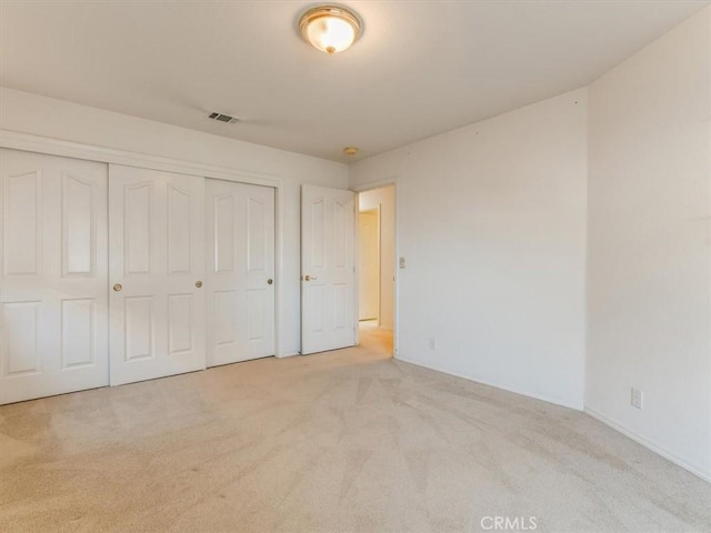 unfurnished bedroom featuring light carpet, a closet, and visible vents