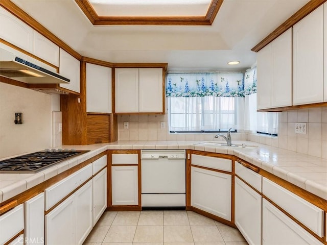 kitchen with white cabinets, a raised ceiling, tile countertops, white dishwasher, and stainless steel gas stovetop