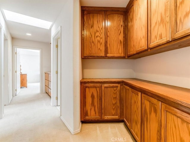 interior space featuring brown cabinetry, a skylight, light countertops, and light carpet