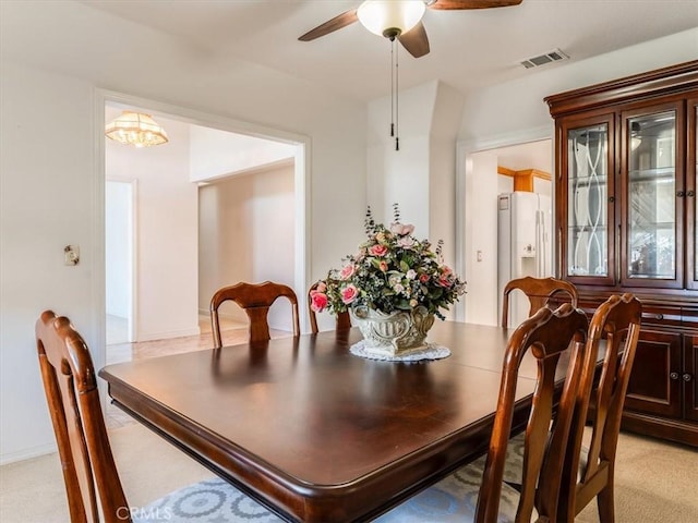 dining room with light carpet, ceiling fan, and visible vents