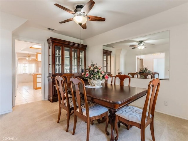 dining space featuring light tile patterned floors, ceiling fan, visible vents, and light colored carpet