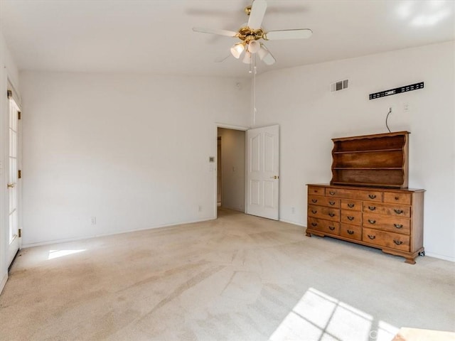 unfurnished bedroom featuring lofted ceiling, a ceiling fan, visible vents, and light colored carpet