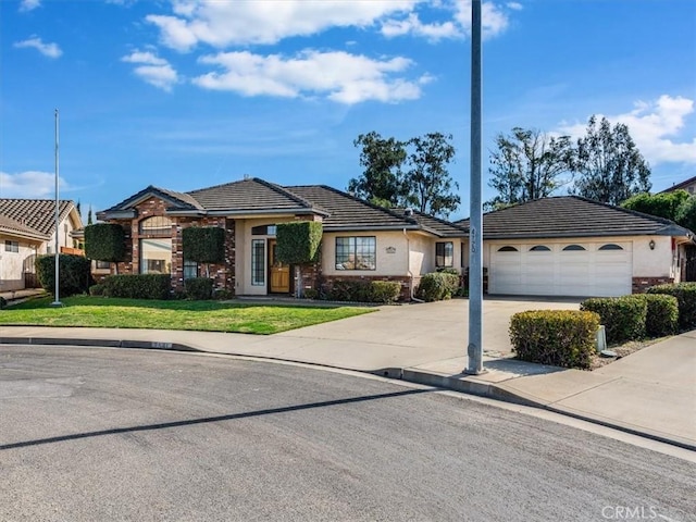 view of front of property featuring stucco siding, concrete driveway, an attached garage, a tiled roof, and a front lawn