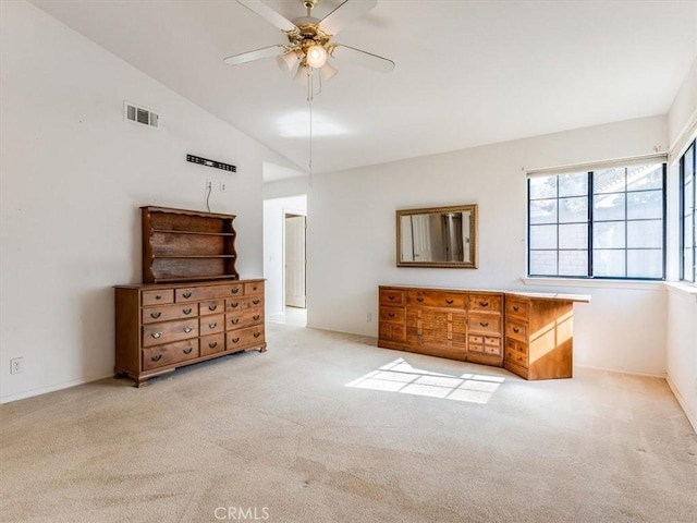 unfurnished bedroom featuring visible vents, vaulted ceiling, a ceiling fan, and light colored carpet