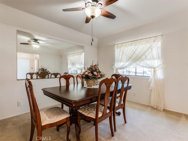 carpeted dining space with ceiling fan and baseboards