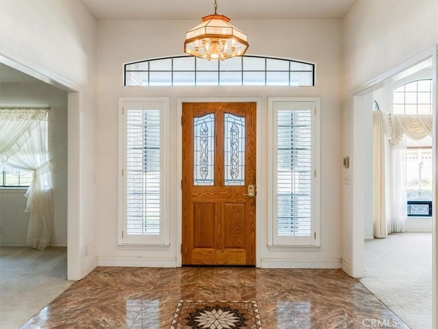 foyer with marble finish floor, baseboards, and carpet flooring