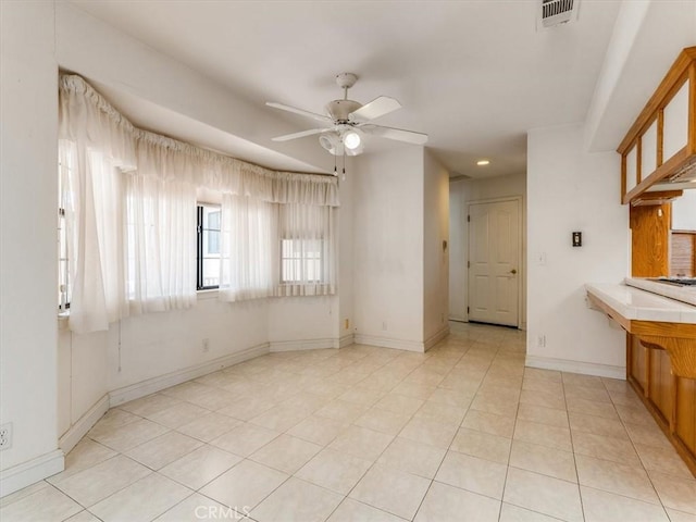 interior space with visible vents, ceiling fan, baseboards, and light tile patterned floors