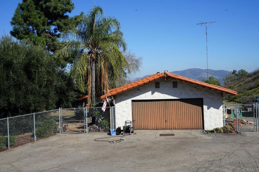 view of outdoor structure featuring a gate, fence, a mountain view, and an outbuilding