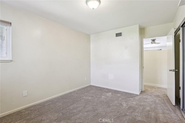 spare room featuring light colored carpet, visible vents, and baseboards