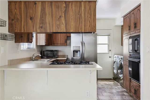 kitchen featuring a peninsula, stainless steel appliances, light countertops, and washer and dryer