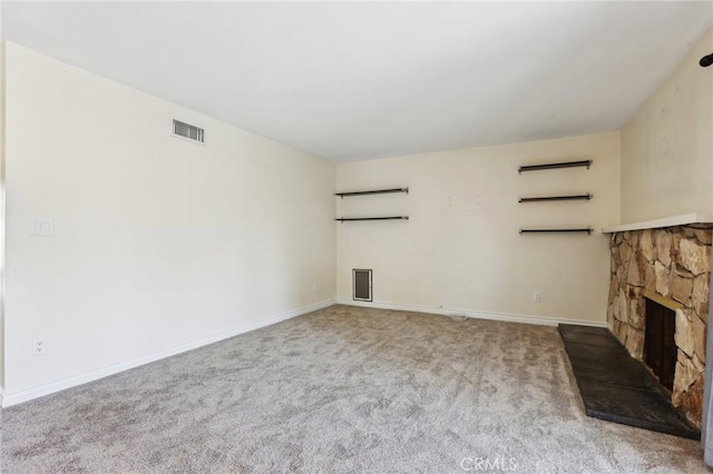 unfurnished living room featuring light carpet, a fireplace, visible vents, and baseboards