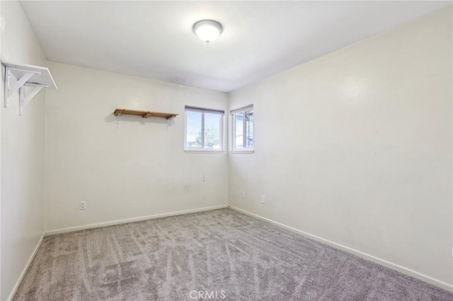 spare room with baseboards and light colored carpet