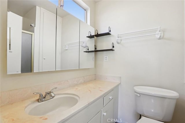 bathroom with a stall shower, vanity, and toilet