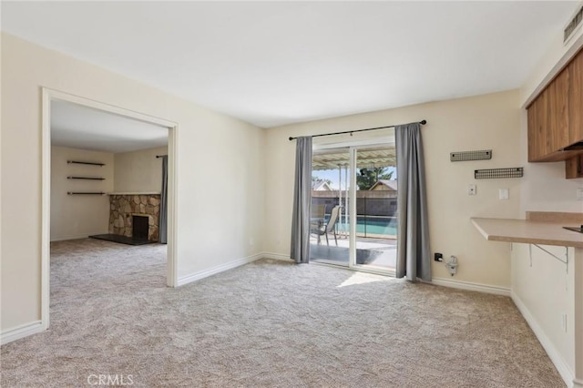 unfurnished living room featuring baseboards, a fireplace, and light colored carpet