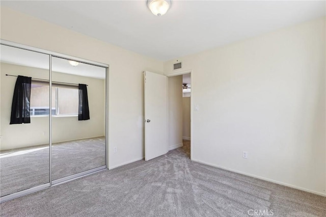 unfurnished bedroom featuring baseboards, a closet, visible vents, and light colored carpet