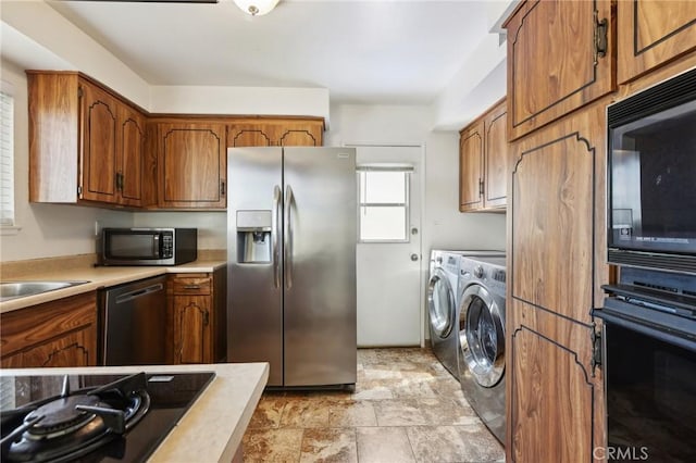 kitchen with light countertops, stone finish floor, brown cabinets, black appliances, and washer and clothes dryer