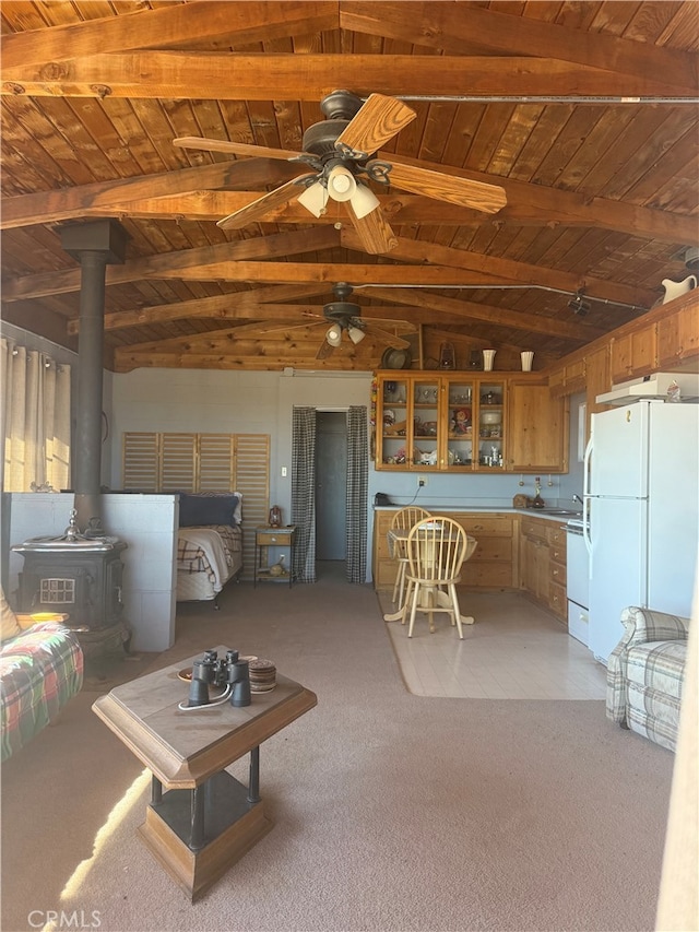 unfurnished living room featuring wood ceiling, a wood stove, light carpet, and vaulted ceiling with beams