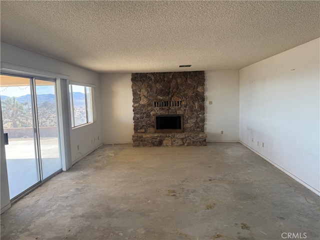 unfurnished living room with a textured ceiling, a stone fireplace, unfinished concrete flooring, and visible vents