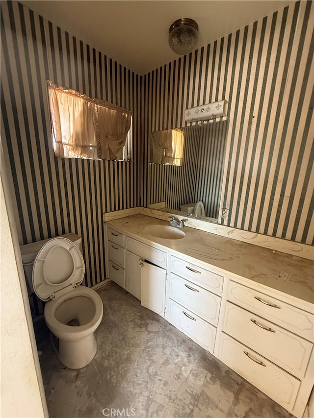 bathroom featuring vanity, toilet, and wallpapered walls