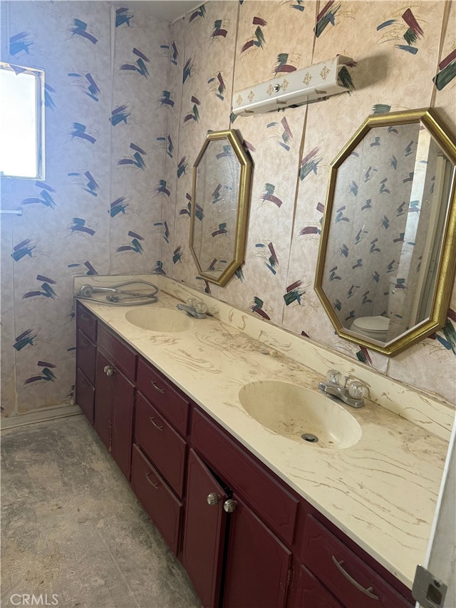 full bathroom featuring double vanity, a sink, and toilet