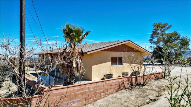 view of side of property featuring roof with shingles and stucco siding