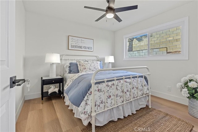 bedroom featuring a ceiling fan, baseboards, and wood finished floors