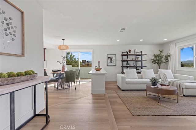 living room with light wood-style floors, visible vents, a wealth of natural light, and recessed lighting