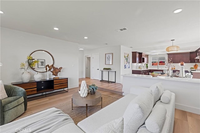 living room with recessed lighting, baseboards, visible vents, and light wood finished floors