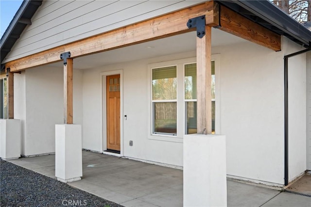 property entrance with a patio and stucco siding