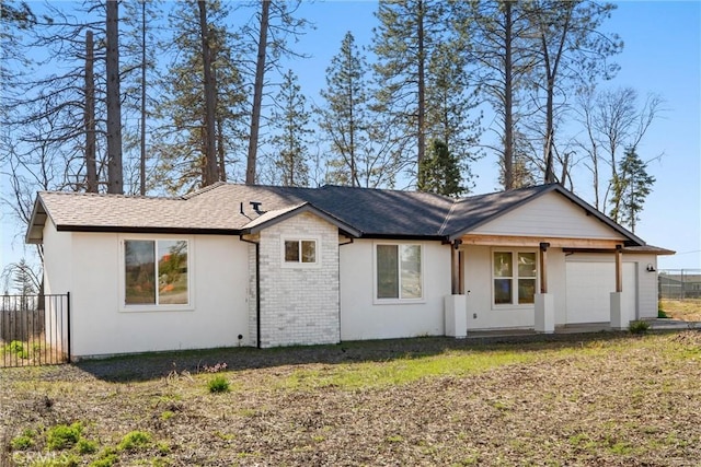 exterior space featuring an attached garage, fence, and brick siding