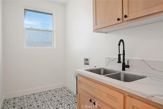 kitchen featuring light tile patterned floors, baseboards, light stone countertops, light brown cabinetry, and a sink