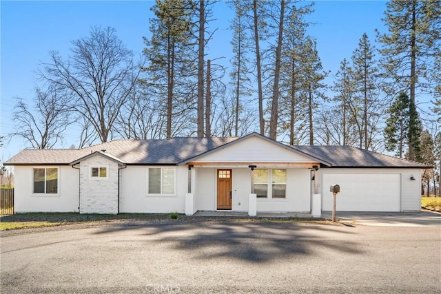 ranch-style house featuring covered porch, brick siding, driveway, and an attached garage