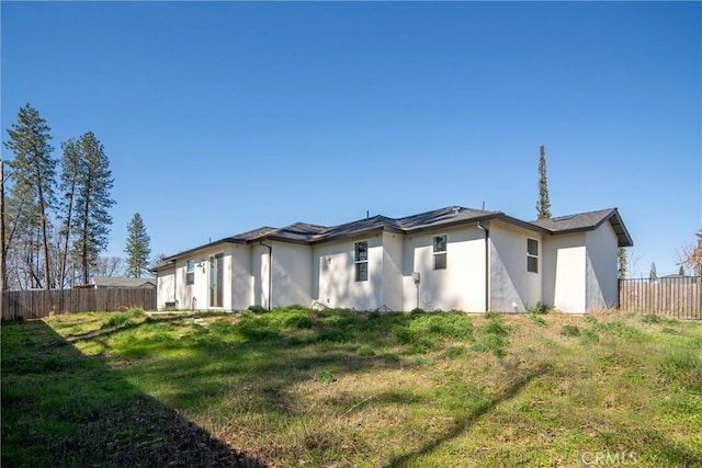 back of house with a lawn, fence, and stucco siding