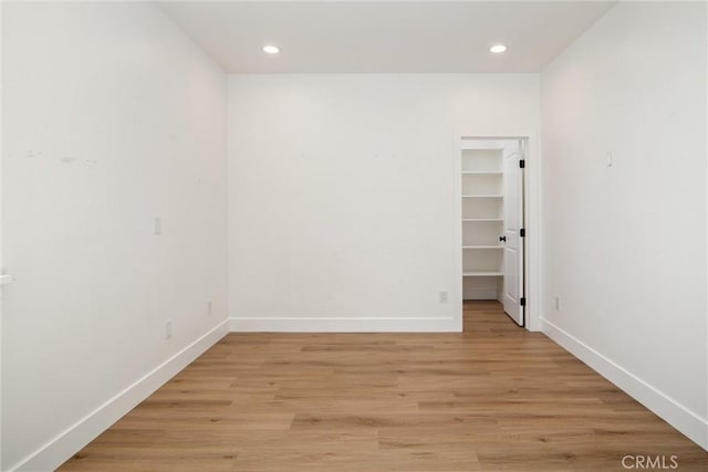 empty room with baseboards, recessed lighting, and light wood-style floors