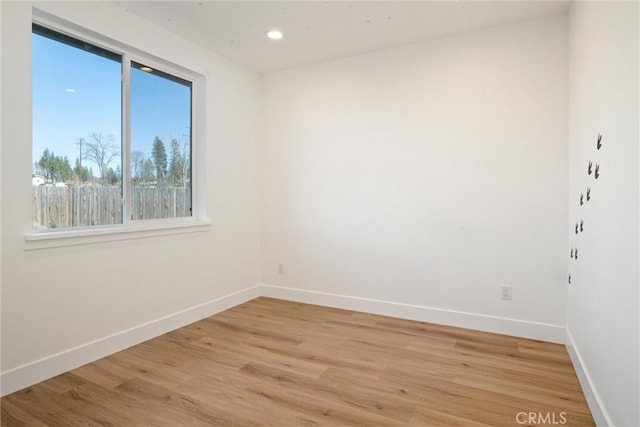 empty room featuring light wood finished floors, baseboards, and recessed lighting