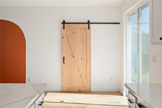 interior space with a barn door, arched walkways, and light wood-style flooring