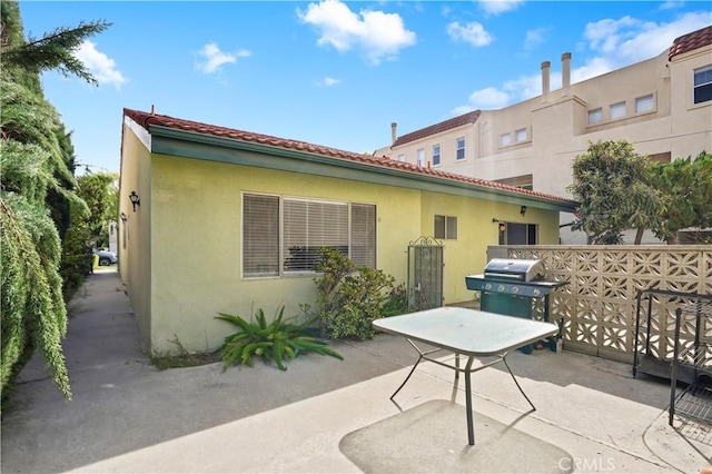 rear view of house with a tiled roof, a patio area, and stucco siding