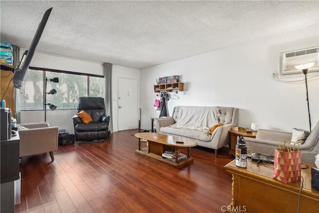 living area featuring a wall unit AC, dark wood finished floors, and a textured ceiling