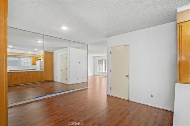 empty room with a textured ceiling and dark wood-style flooring