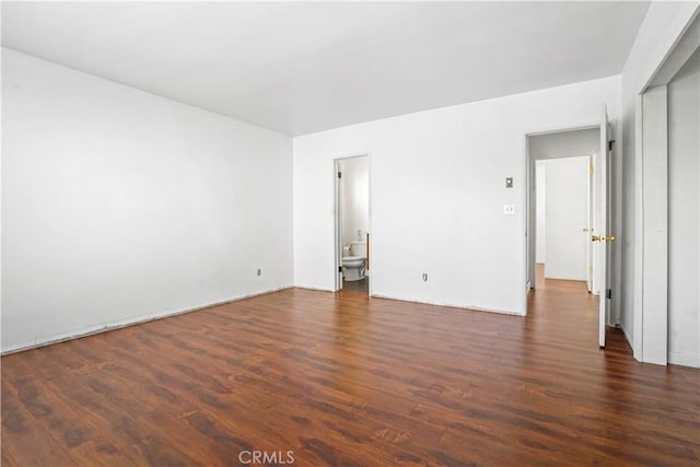 unfurnished bedroom featuring ensuite bathroom and dark wood-type flooring