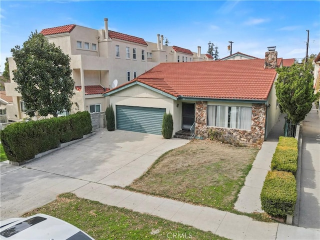 mediterranean / spanish home featuring an attached garage, a tile roof, stone siding, driveway, and stucco siding