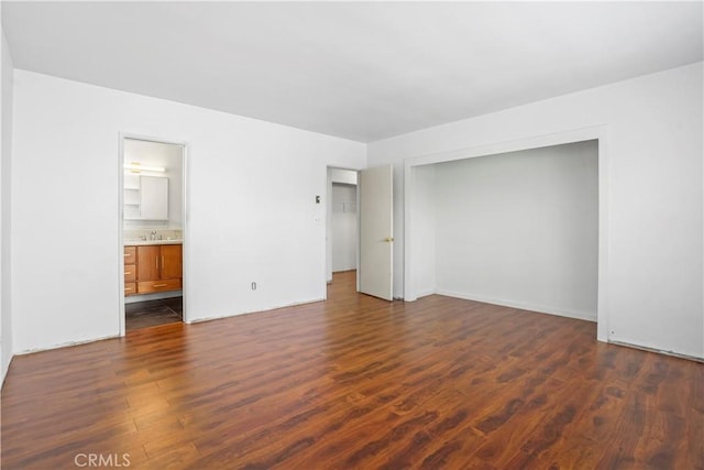 unfurnished bedroom featuring dark wood-style floors, a closet, and ensuite bathroom