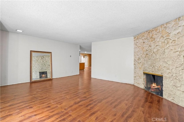 unfurnished living room with a textured ceiling, a fireplace, and wood finished floors